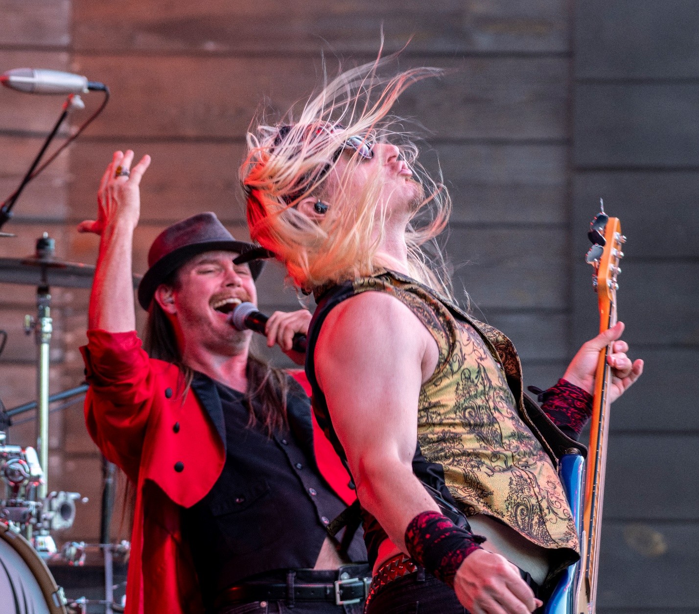 Concert singer singing behind guitarist whipping long blonde hair