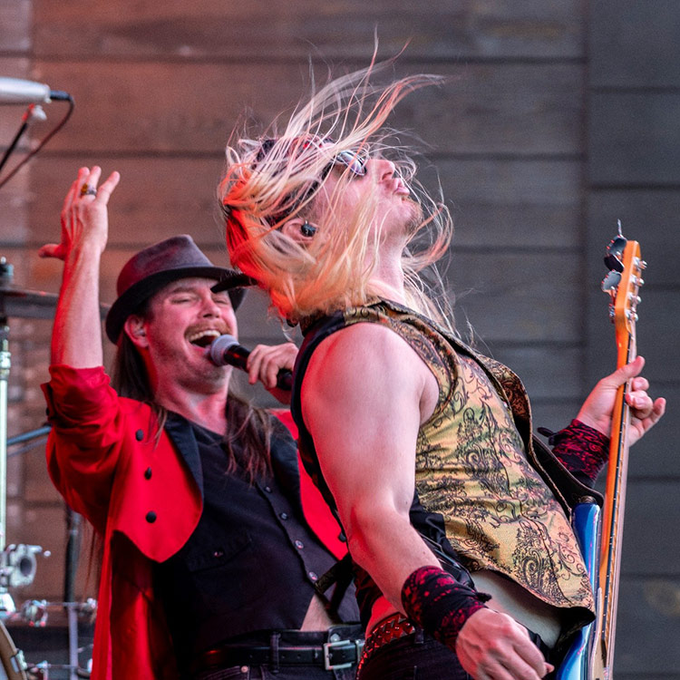 Concert singer singing behind guitarist whipping long blonde hair